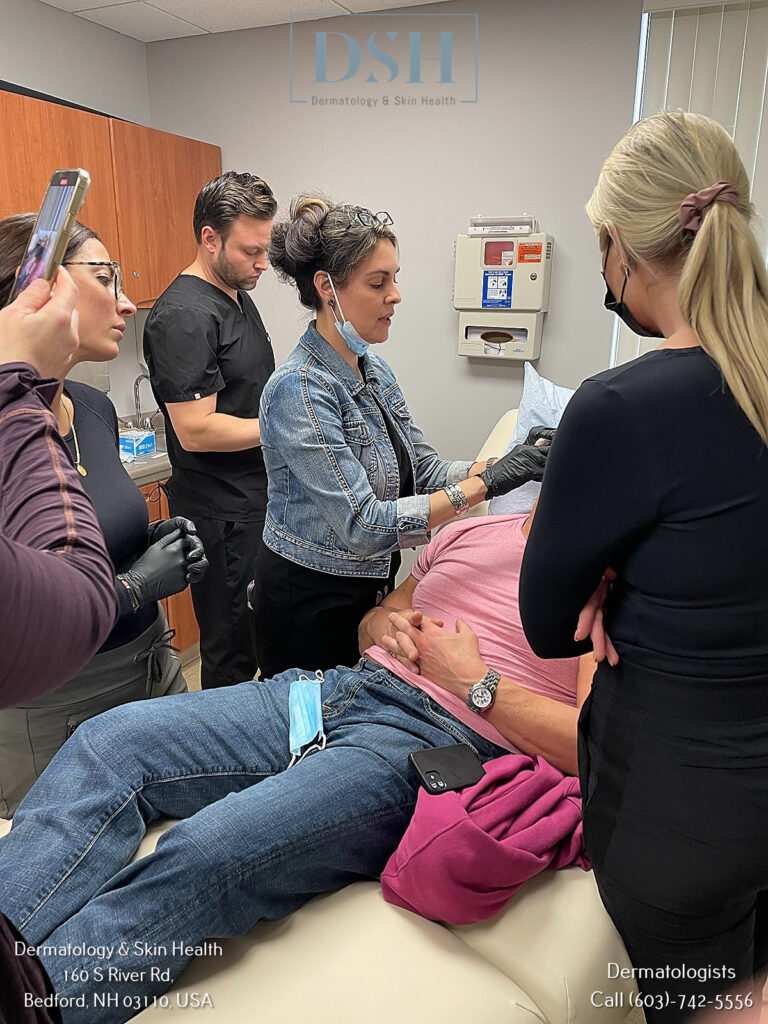 A dermatology procedure with a patient lying down, surrounded by a medical team examining and treating her in a clinic room.
