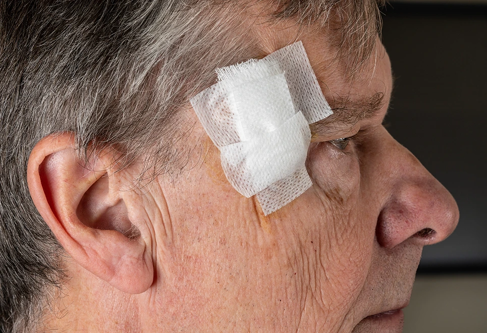 Close-up of an elderly man's profile with a medical bandage on his temple.