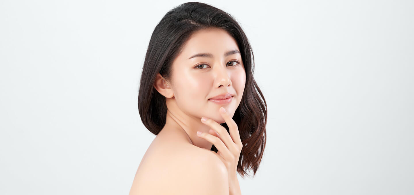 A young asian woman posing with her hand on her face.