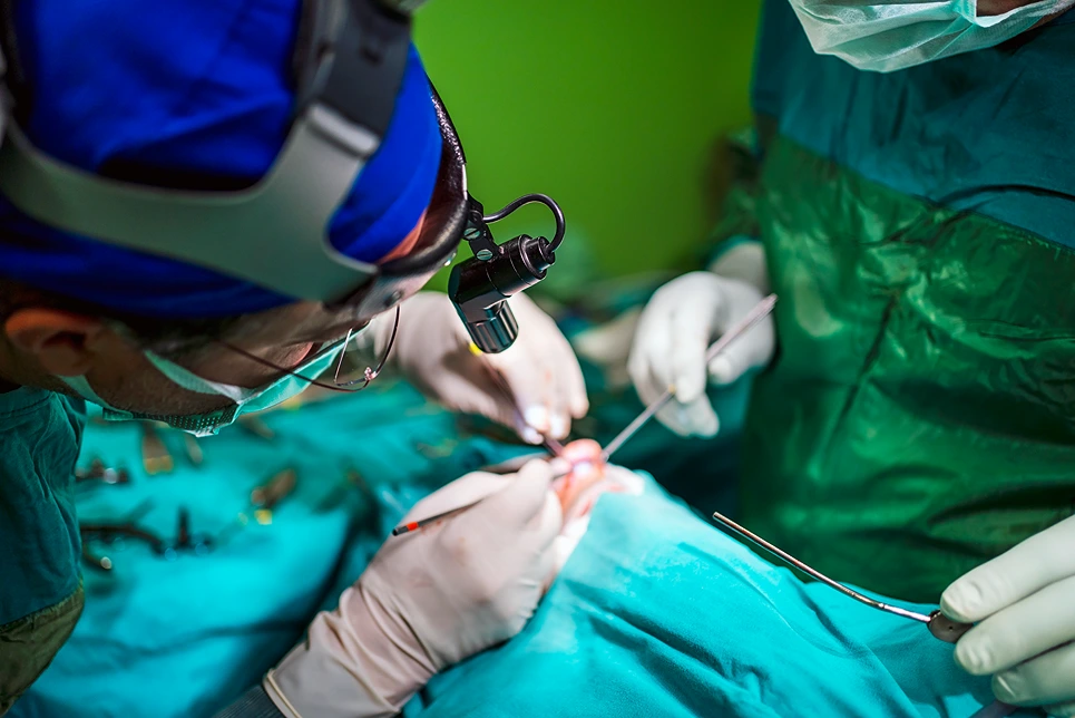 Two surgeons performing surgery on a patient.