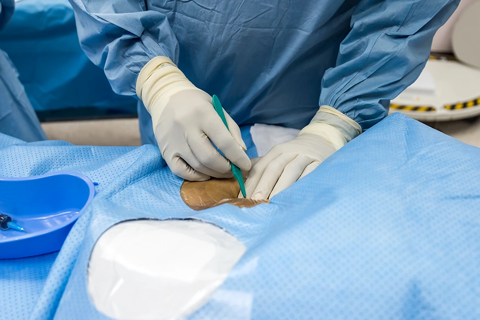 A surgeon is working on a patient in an operating room.