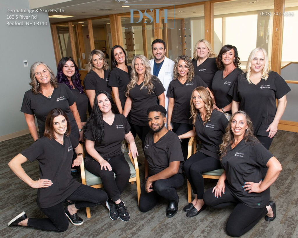 Group of healthcare professionals in uniforms posing for a team photo in a clinic setting.