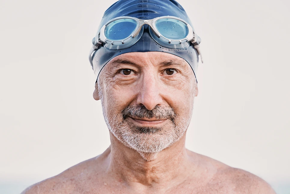 Portrait of a mature male swimmer wearing goggles and a swim cap.