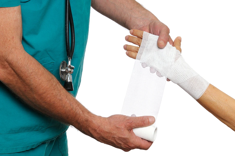 Healthcare professional wrapping a patient's wrist with a bandage.
