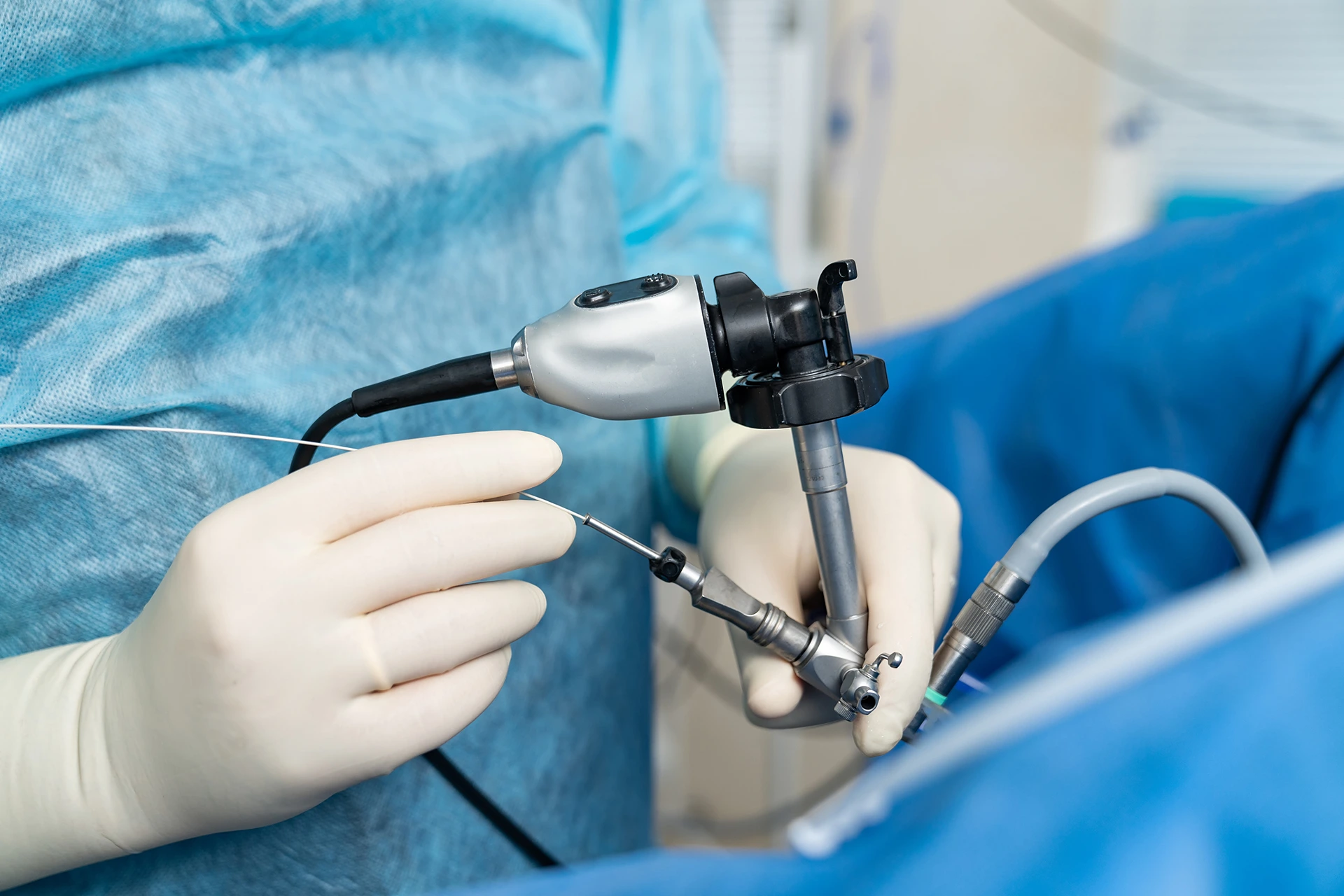 A healthcare professional in blue scrubs holding an endoscope during a medical procedure.